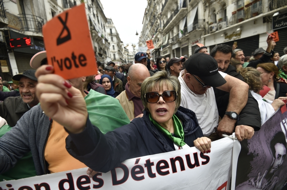 Algerian protesters lift banners as they take part in an anti-government demonstration in the center of the capital Algiers on Friday. — AFP