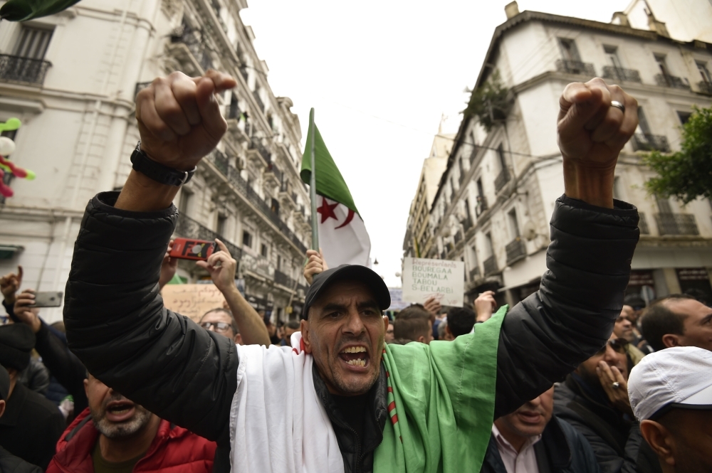 Algerian protesters lift banners as they take part in an anti-government demonstration in the center of the capital Algiers on Friday. — AFP