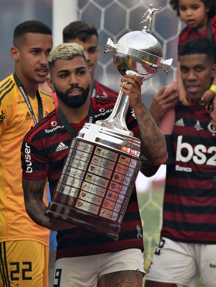 Players of Brazil's Flamengo celebrate on the podium with the trophy after winning the Copa Libertadores final football match by defeating Argentina's River Plate, at the Monumental stadium in Lima, on Saturday. — AFP