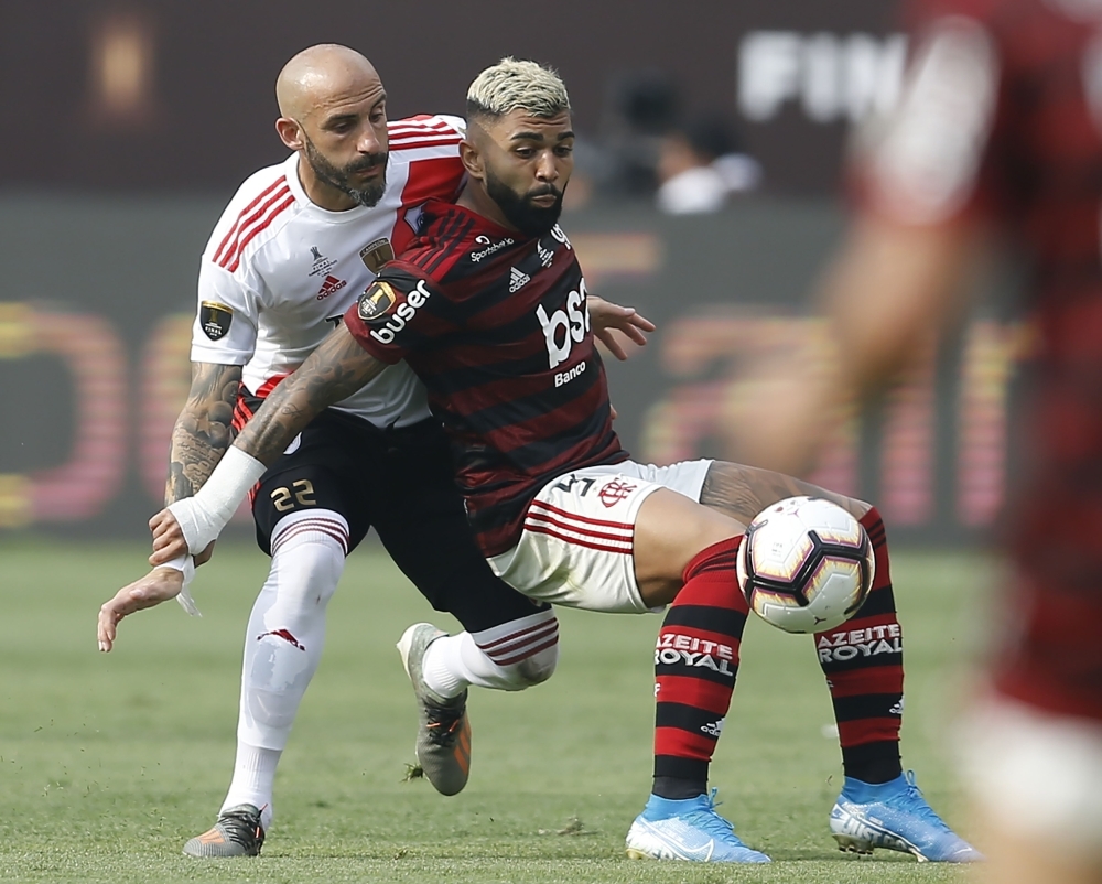 Players of Brazil's Flamengo celebrate on the podium with the trophy after winning the Copa Libertadores final football match by defeating Argentina's River Plate, at the Monumental stadium in Lima, on Saturday. — AFP