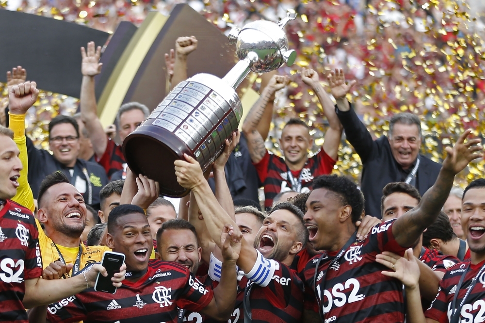 Players of Brazil's Flamengo celebrate on the podium with the trophy after winning the Copa Libertadores final football match by defeating Argentina's River Plate, at the Monumental stadium in Lima, on Saturday. — AFP