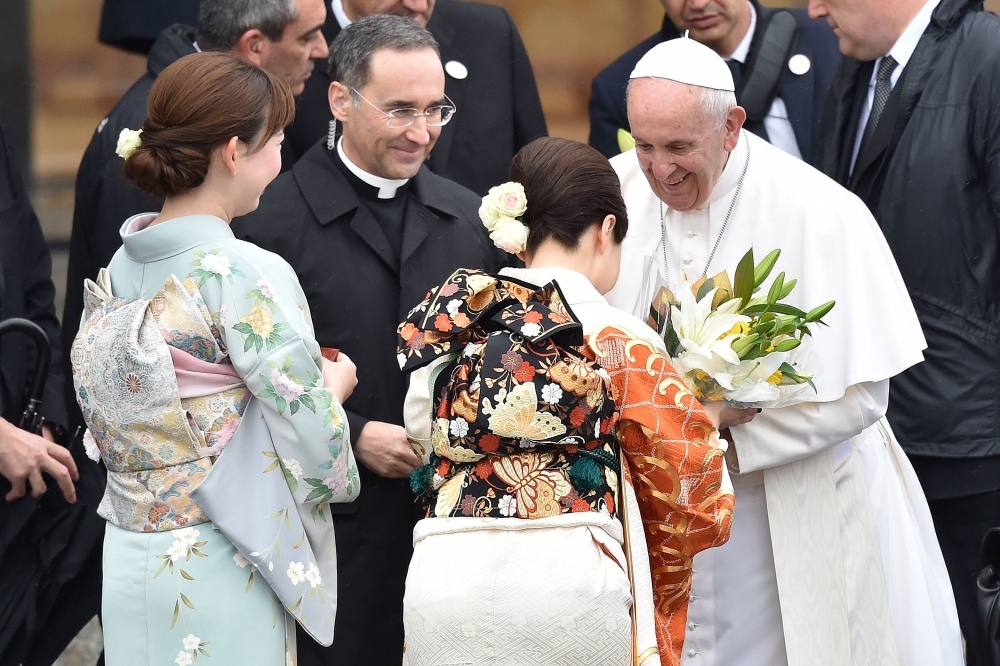 Pope receives flowers from women dressed in kimonos as he leaves Tokyo's Haneda airport on Tuesday. -AFP
