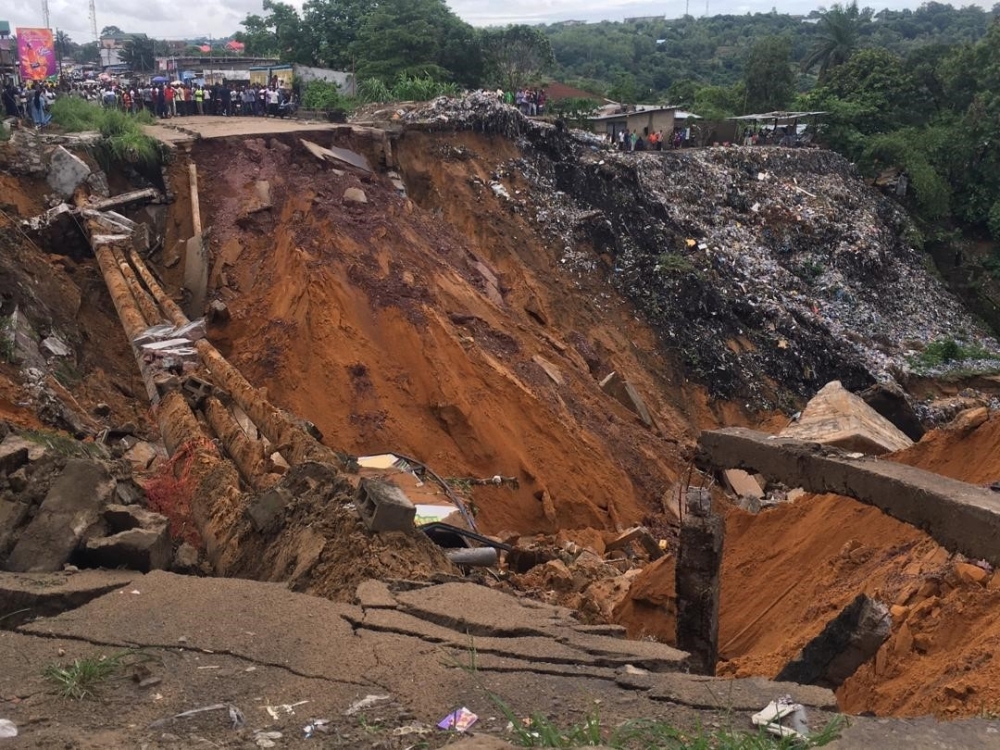 A road surface swept away by a landslide caused by torrential overnight rains is photographed in the Lemba district of Kinshasa on Tuesday. — AFP