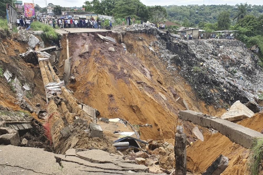 A road surface swept away by a landslide caused by torrential overnight rains is photographed in the Lemba district of Kinshasa on Tuesday. — AFP