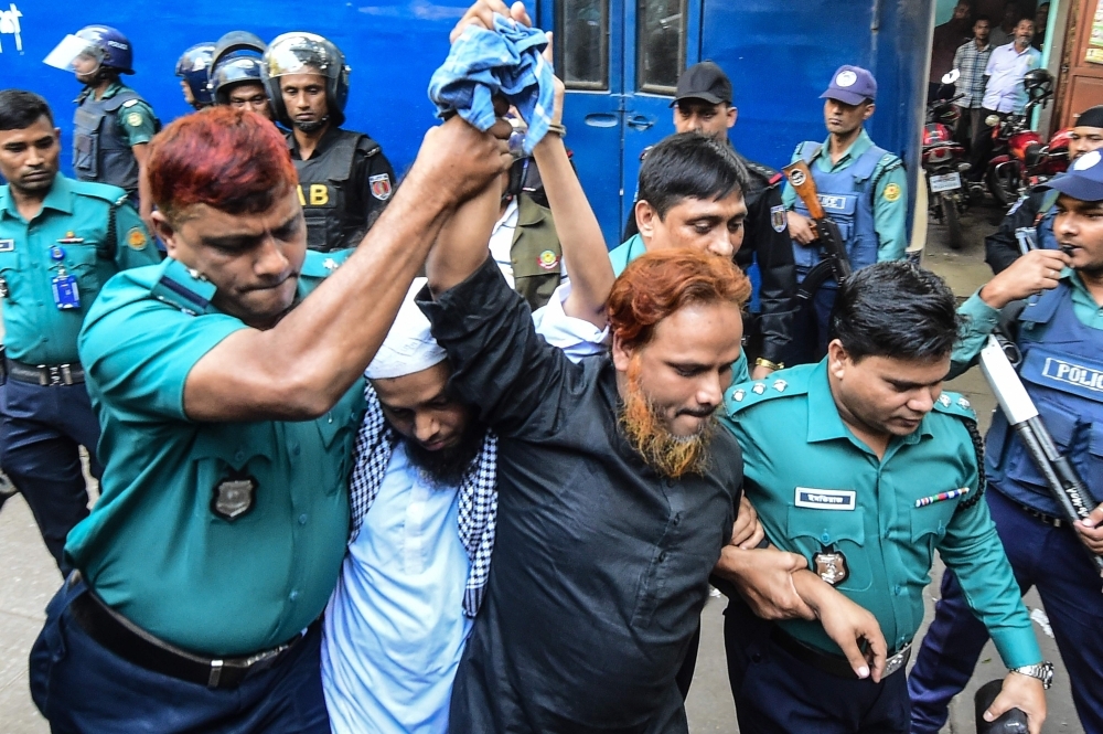 Police escort extremists, center, accused of allegedly plotting the Holey Artisan Bakery cafe attack, carried out by militants, to a courtroom for their trial in Dhaka on Wednesday. — AFP