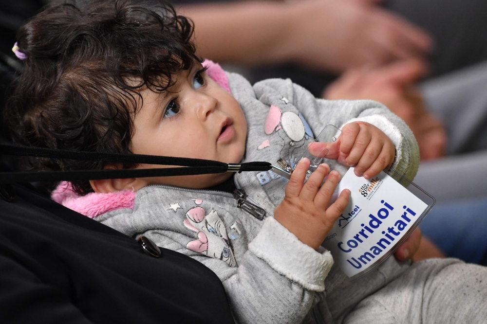 Syrian refugees Ibrahim Bitar, 42, rear right with red jersey, and his sister Iman Bitar, center from behind, react after arriving with other Syrian refugees at Rome's Fiumicino international airport as part of a humanitarian corridor on Wednesday. — AFP