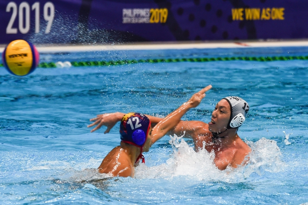 Koh Jian Yang of Singapore (R) shoots past Juan Serrano Paolo of the Philippines during the men's water polo round robin match between Singapore and Philippines at the SEA Games (Southeast Asian Games) at the Aquatics Center in Clark on Friday. — AFP