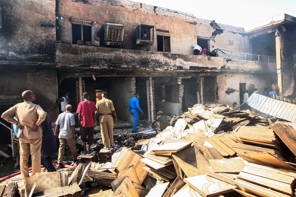 A Sudanese paramedic walks with a stretcher as others search for victims at the scene of a fire at a tile manufacturing unit in an industrial zone in north Khartoum on Tuesday. — AFP