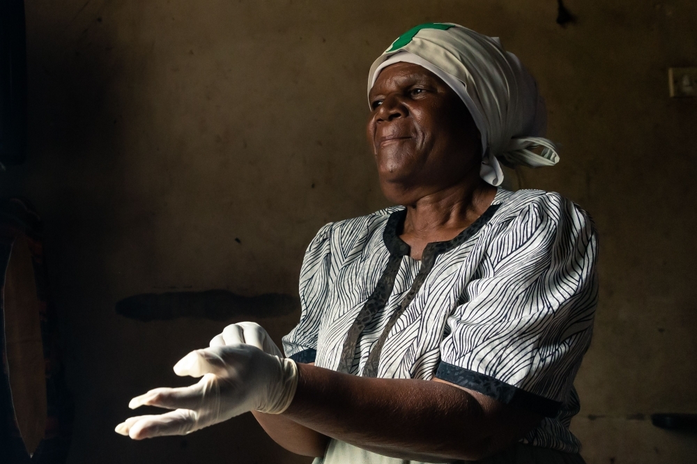 Sixty-nine-year-old Esther Gwena, an untrained midwife  adjusts a pair of surgical gloves as she prepares herself for a long day ahead at her two-room apartment in Mbare high-density suburb in Harare, on November 21, 2019. -AFP