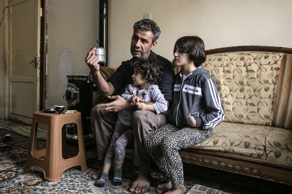 Displaced from the border town of Ras Al-Ain, Syrian Kurdish film director Teymour Ifdaki, 42, who's home was allegedly burned along with his collection of 500 books by Turkey-backed Syrian fighters, sits with his two daughters in a house in the de-facto Syrian Kurdish capital of Qamishli, in this Nov. 28, 2019 file photo. — AFP