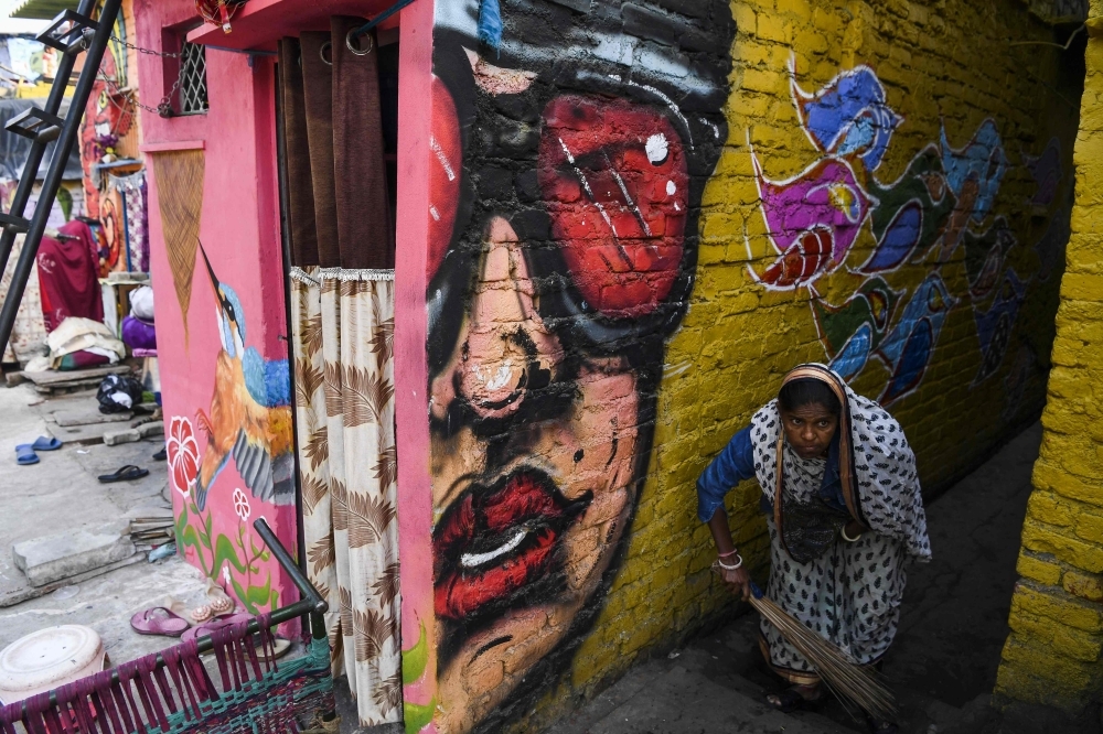 Local residents shop from a store next to a home adorned with a mural painted by artists from 'Delhi Street Art' group at the Raghubir Nagar slum in New Delhi in this Dec. 2, 2019 file photo. — AFP