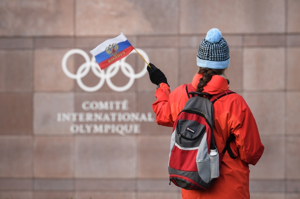 In this file photograph taken on Dec. 5, 2017, a supporter waves a Russian flag in front of the logo of the International Olympic Committee (IOC) at their headquarters in Pully near Lausanne. In Russia, where criticism of the authorities can lead to dire consequences, the head of the country's anti-doping agency Yury Ganus has openly accused officials of tampering with data handed to the global watchdog. — AFP