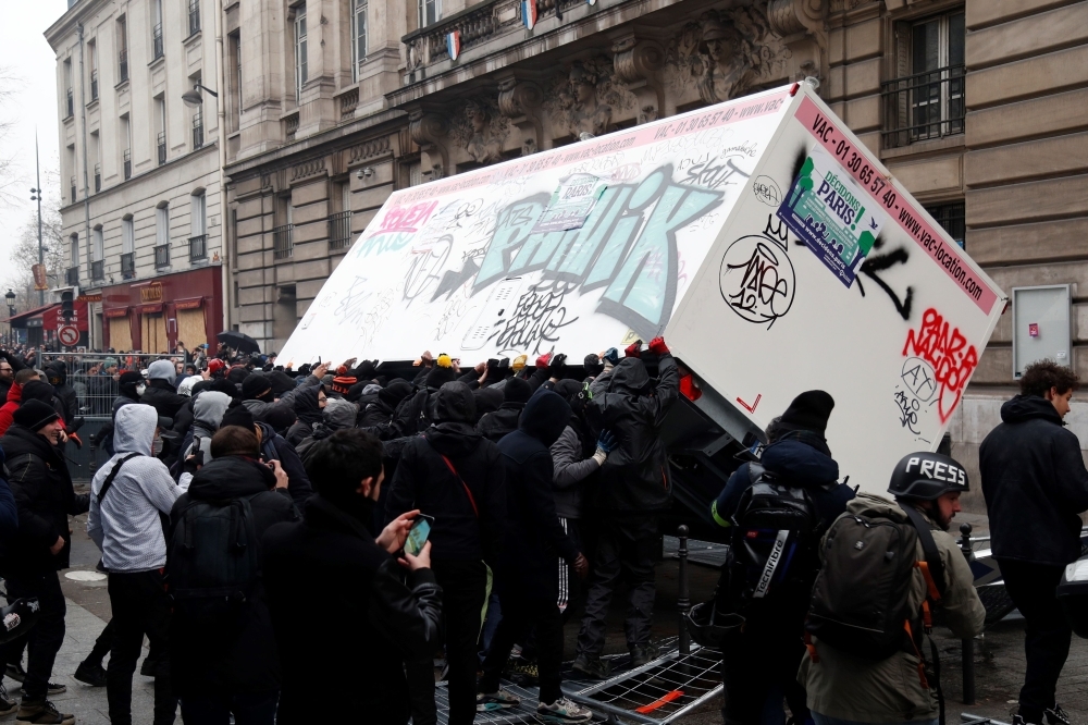 CRS riot police stand as fire is seen in the background during a rally against the pension overhauls, in Paris, on Thursday. — AFP