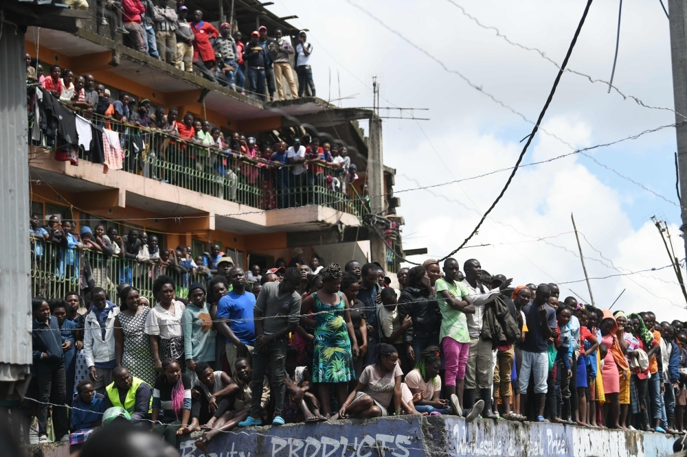 Curios onlookers stand around the scene of a collapsed six-story building in Nairobi, as search and rescue continue, on Friday. — AFP