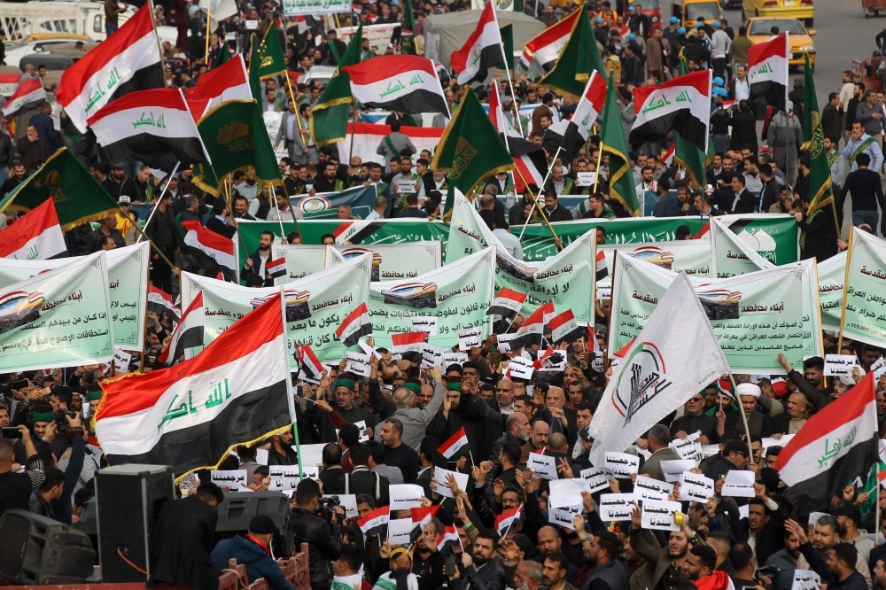 An Iraqi demonstrator waves a large national flag in the capital Baghdad's Tahrir Square, amid ongoing anti-government protests, on Friday. -AFP. 