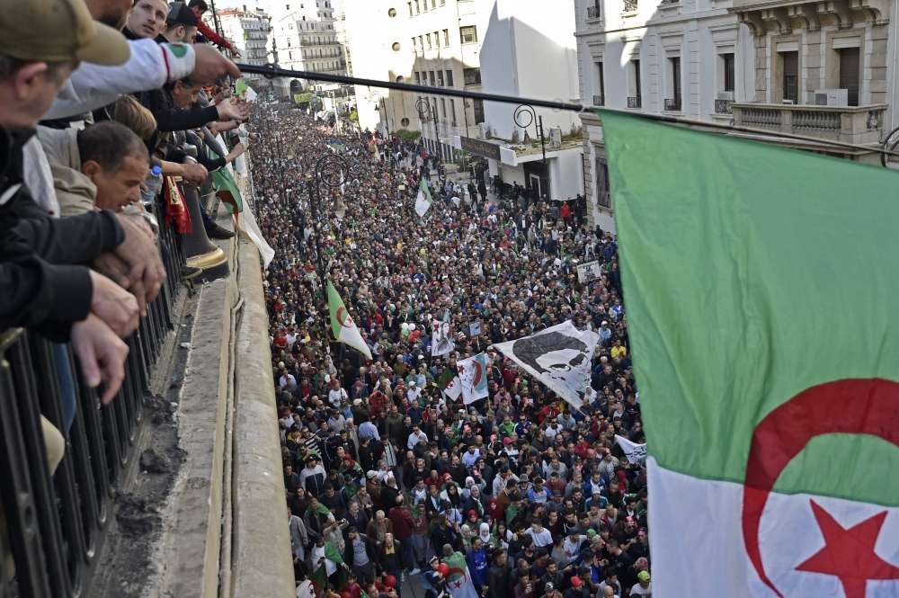 Algerians wave a national flag from a balcony as they watch anti-government demonstrators march in the capital Algiers on December 6, 2019, ahead of the presidential vote scheduled for December 12. -AFP