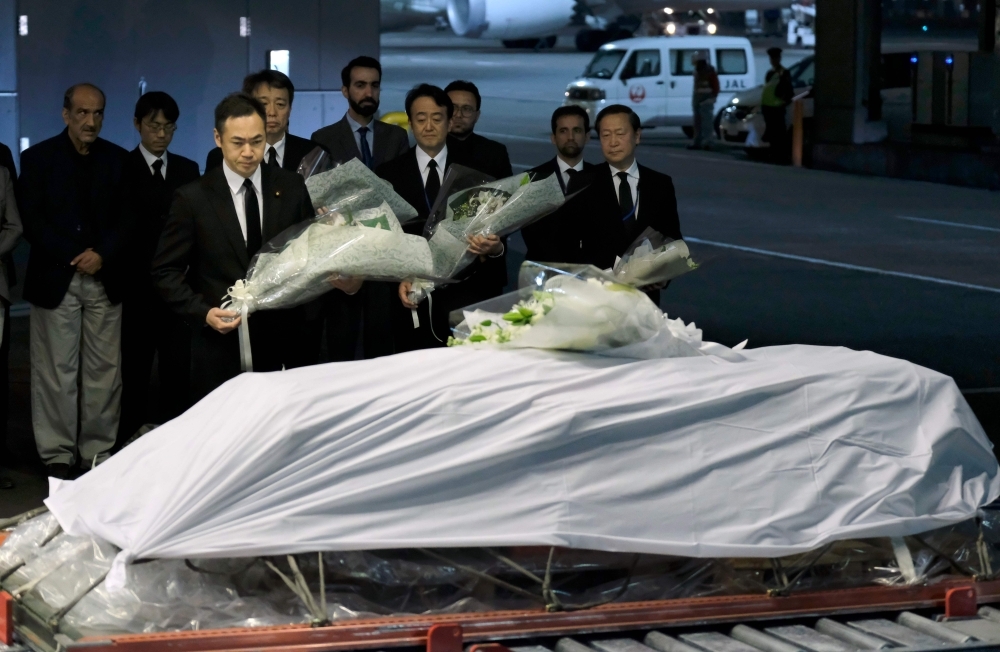 Keisuke Suzki (C), Japan's State Minister for Foreign Affairs, offers a bouquet over late Japanese physician Tetsu Nakamura's coffin upon arrival at Narita Airport in Chiba prefecture on Sunday. -AFP