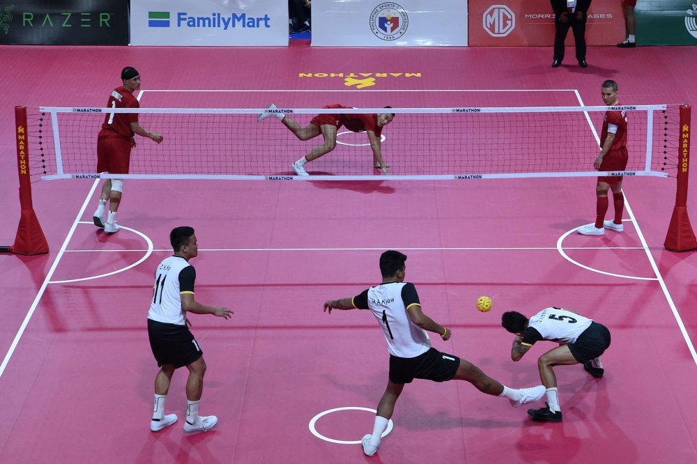 Thailand (in red) and Myanmar (in white) players compete during the sepak takraw match at the SEA Games (Southeast Asian Games) at the Subic Bay Metroplitan Authority in Subic, northwest of Manila, on Sunday. — AFP