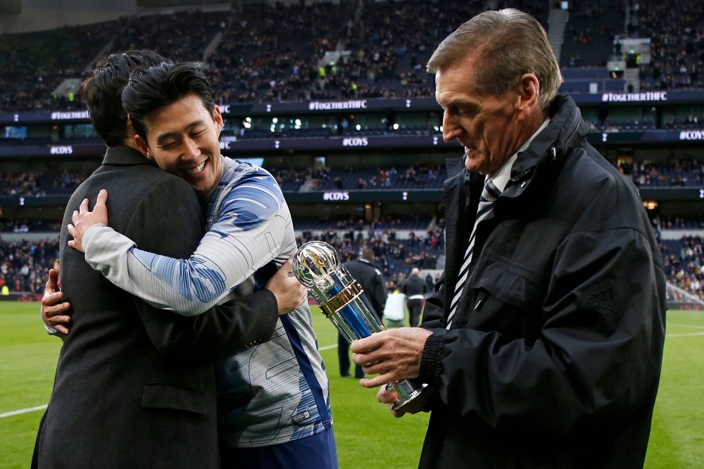 Tottenham Hotspur's South Korean striker Son Heung-min (C) embraces an ambassador for the AFC as former Scotland manager Andy Roxburgh (R) studies his trophy after Son is named AFC Asian International Player of the Year for a third time before the English Premier League football match between Tottenham Hotspur and Burnley at Tottenham Hotspur Stadium in London, on Saturday. — AFP
