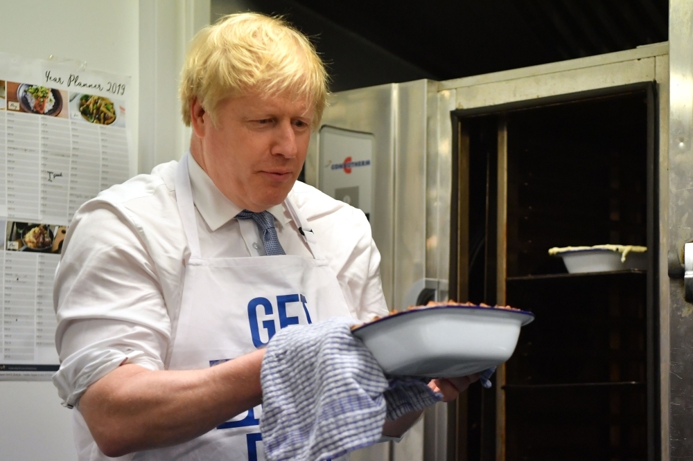 Britain's Prime Minister Boris Johnson prepares a pie at the Red Olive kitchen in Derby, central England, on Wednesday. — AFP