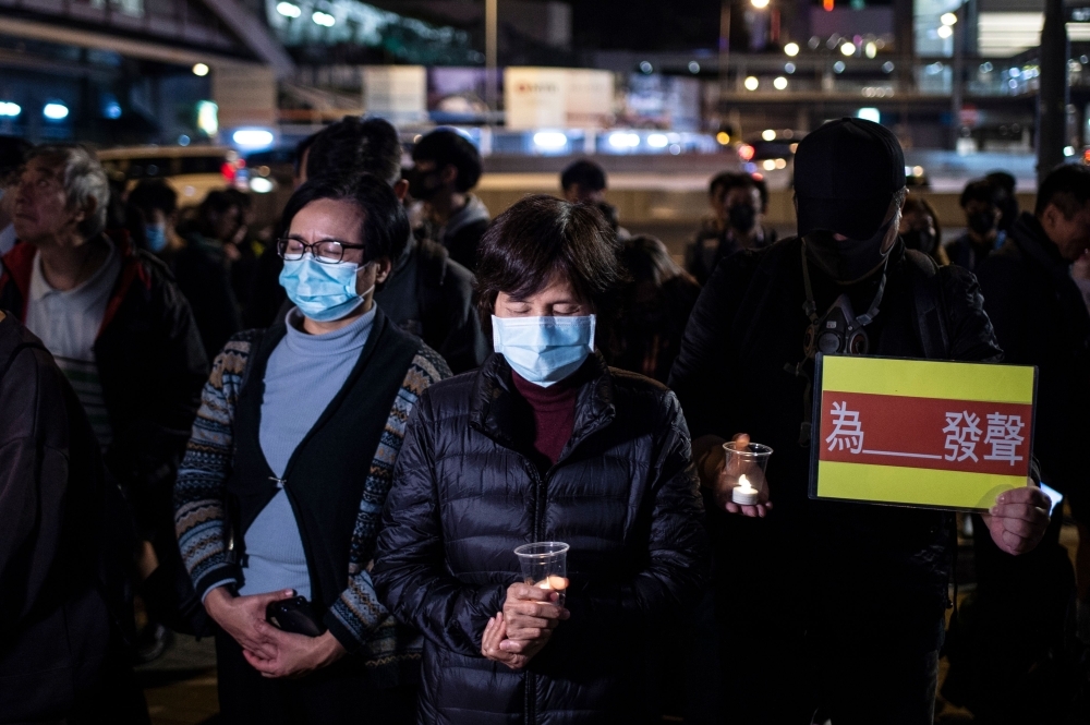 People hold electronic candles and placards during a Human Rights Day rally in Hong Kong on Tuesday. — AFP