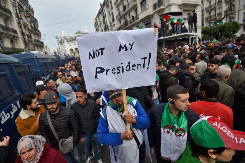An Algerian protester lifts a placard in the capital Algiers on Friday as he takes part in a demonstration to reject the results of the presidential elections. — AFP