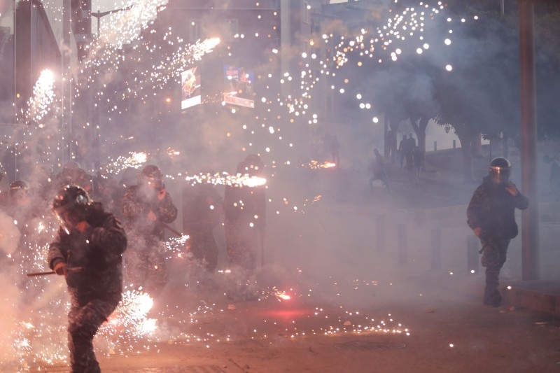 Lebanese riot police react to fireworks thrown by supporters of Lebanon's Shiite Hezbollah and Amal groups during clashes on Saturday in central Beirut. — AFP