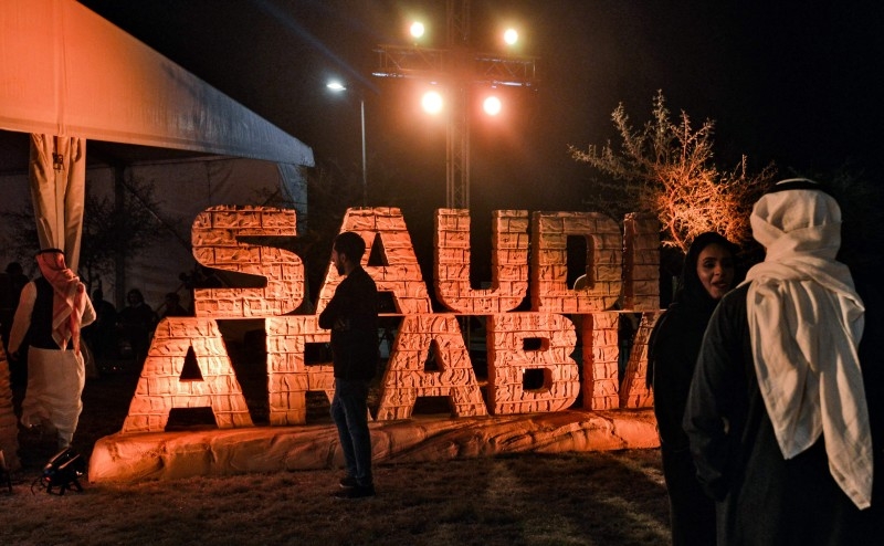 People stand before a sign showing the logo of the Dakar Saudi Arabia 2020 rally, during a press conference about the event in Qiddiya.