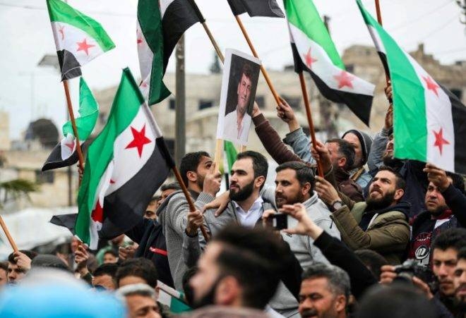 Syrian protesters wave the three-star flag of the opposition in Maaret Al-Numan on March 15, 2019. — AFP file photo