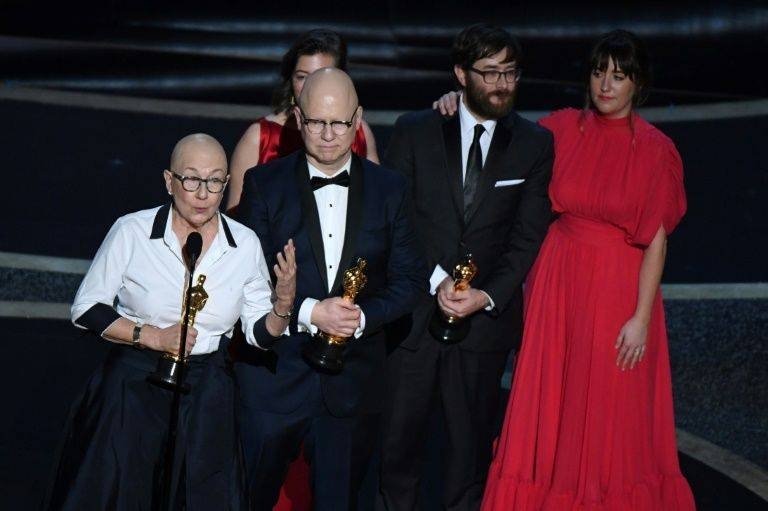 US directors Steven Bognar, center, and Julia Reichert, left, accept the Oscar for best documentary feature for 'American Factory.' — AFP