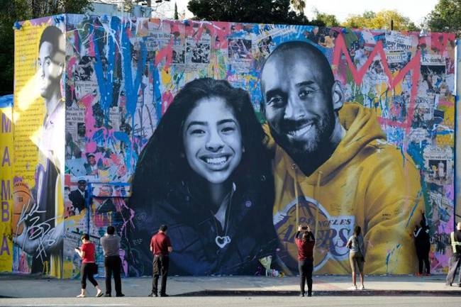 People stop to take pictures in front of the new mural by French artist Mr. Brainwash picturing Kobe Bryant and his daughter Gigi in Los Angeles on Jan. 31, 2020. — AFP