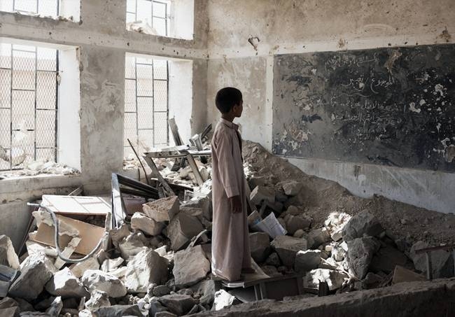 File photo shows a student standing in the ruins of one of his former classrooms, which was destroyed in June 2015, at the Aal Okab school in Saada, Yemen.