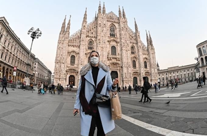 A woman with a protective facemask walks across the Piazza del Duomo, in front of the Duomo, in central Milan, on February 24, 2020, following security measures taken in northern Italy against the COVID-19 the novel coronavirus. — AFP