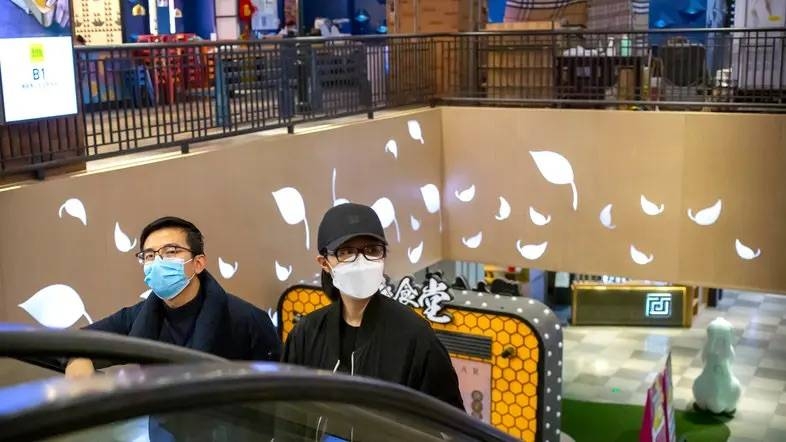 A couple wear face masks as they ride an escalator at a shopping mall in Beijing. — Courtesy photo