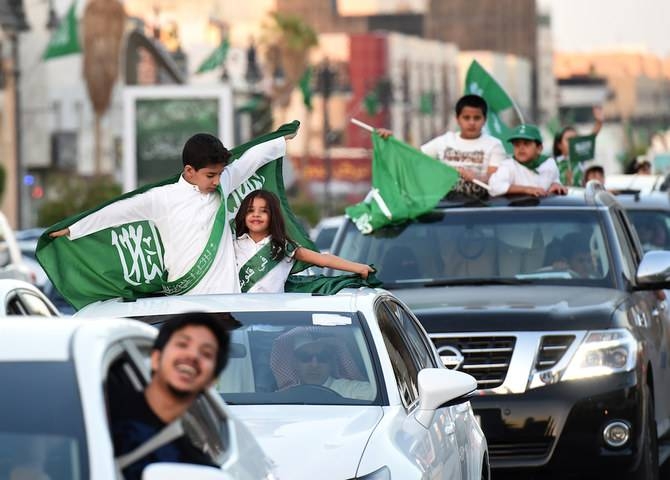 Saudi children wave their national flag as cars drive along the street during celebrations marking the 86th Saudi Arabian National Day in the  kingdom's capital Riyadh, on Sep.23, 2016. — AFP