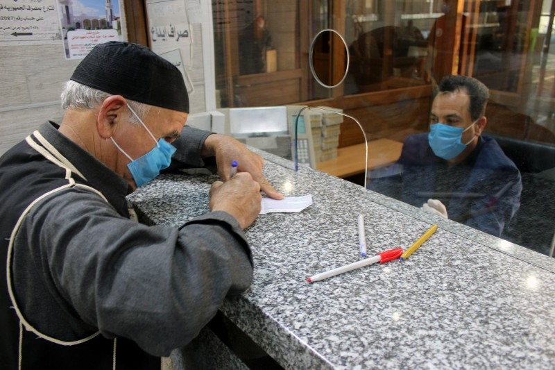 Men wear face masks at a bank in Libya.