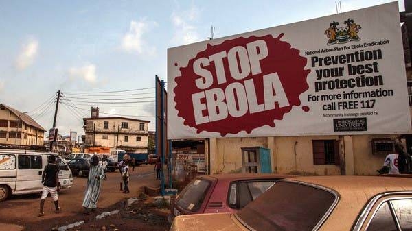 People pass a banner reading ‘STOP EBOLA’ forming part of Sierra Leone's Ebola free campaign in the city of Freetown, Sierra Leone, in this file photo.