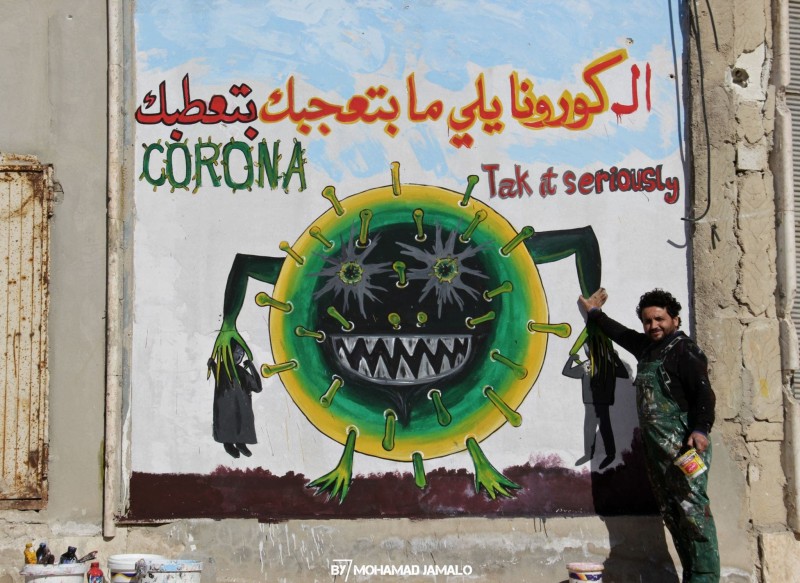 Aziz Asmar with a coronavirus mural in Idlib.

