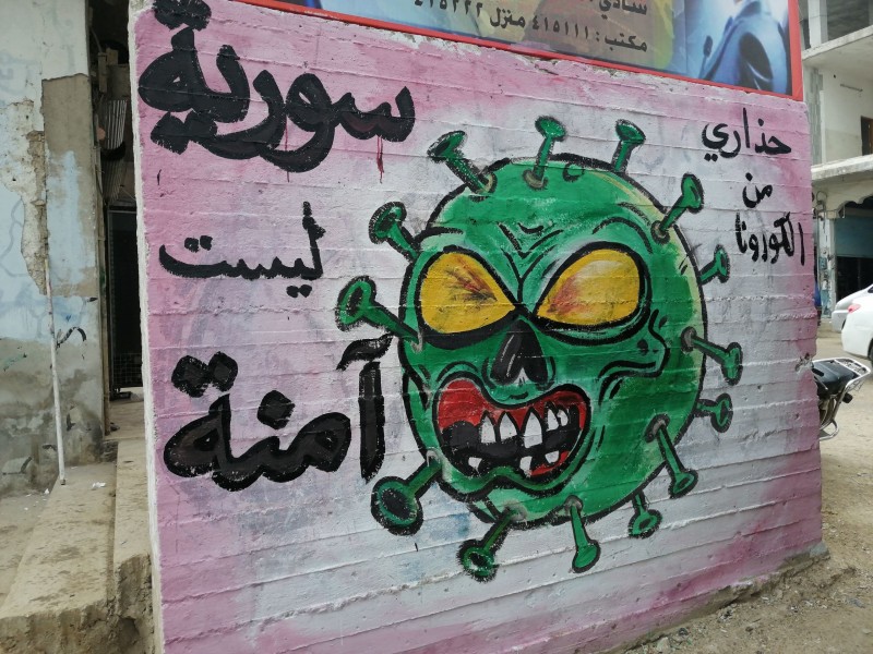 Aziz Asmar with a coronavirus mural in Idlib.

