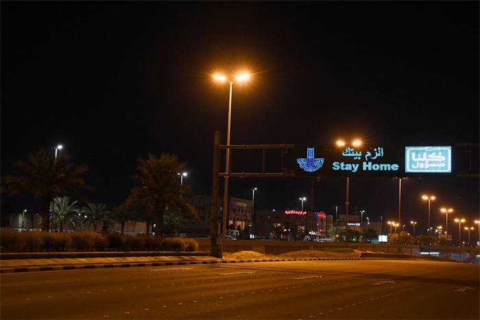 A billboard advising people to Stay Home is seen on a deserted Saudi street during curfew time.