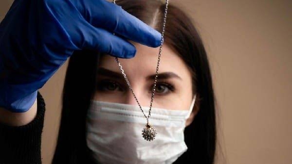 A model wearing a protective mask demonstrates a coronavirus-shaped pendant, which was produced by Dr.Vorobev jewelry company based in Kostroma, Russia. -- Courtesy photo