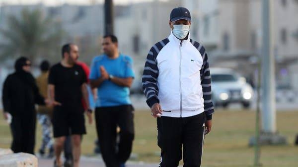 A man wearing a protective face mask walks in Saudi Arabia. Behind him, men are seen without masks. -- File photo
