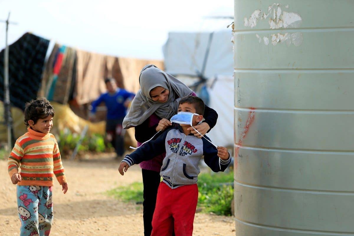 A Syrian refugee woman puts a face mask on a boy as a precaution against the spread of coronavirus, in Al-Wazzani area in southern Lebanon. -- File photo