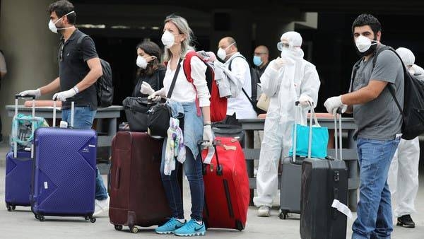 Lebanese people, who were stranded abroad by coronavirus lockdowns, are pictured wearing face masks and gloves as they hold their luggage upon arrival at Beirut's international airport. -- File photo