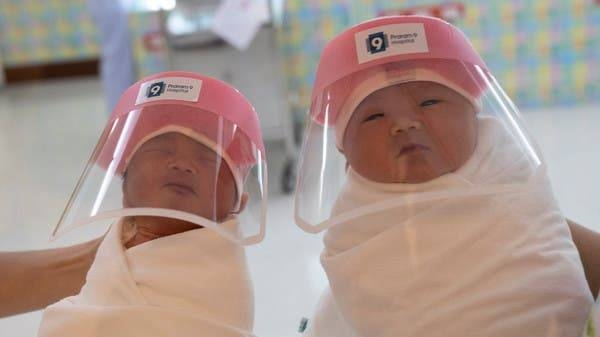 Nurses hold newborn babies wearing protective face shields at the Praram 9 Hospital in Bangkok. -- Courtesy photo
