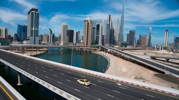 A  lone taxi cab drives over a highway with the Burj Khalifa in the skyline behind it in Dubai. -- File photo
