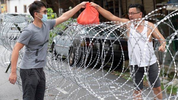 A man collect supplies over barbed wire in the coronavirus locked down area of Selayang Baru, outside of Kuala Lumpur, Malaysia. -- Courtesy photo