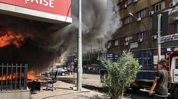 A boy looks on as the Banque Libano Francaise in central Tripoli burns. — Courtesy photo