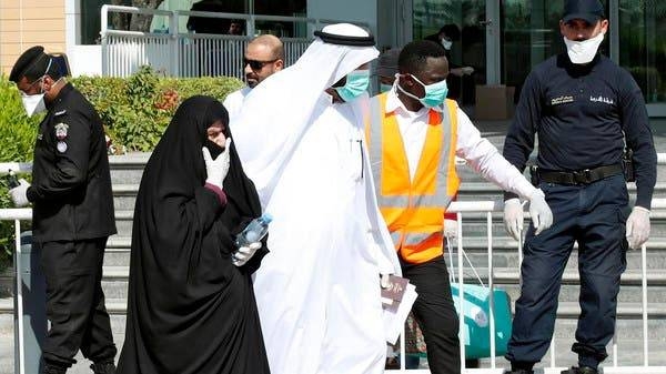 Qatari police stand outside a hotel in Doha as a medical worker walks alongside people wearing masks due to coronavirus. -- File photo

