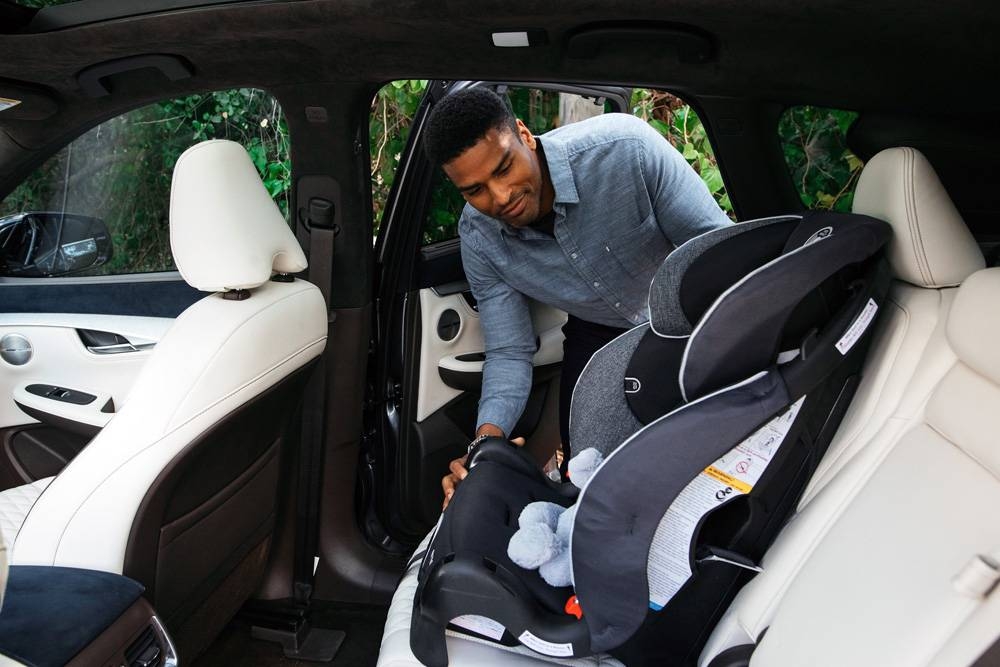 A father fastening seat belt for his son sitting in safety seat in the car.